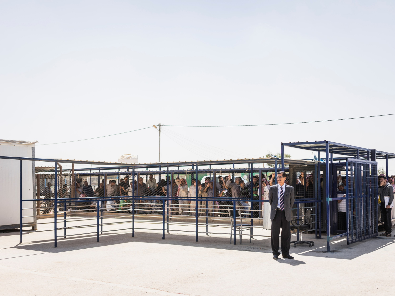 Männer warten am auf den Einlass zu einem Büro im Flüchtlingslager Zaatari, in dem temporäre Arbeitserlaubnisse erteilt werden, Zaatari, Jordanien, 22.08.2017. © Sebastian Wells / Agentur OSTKREUZ