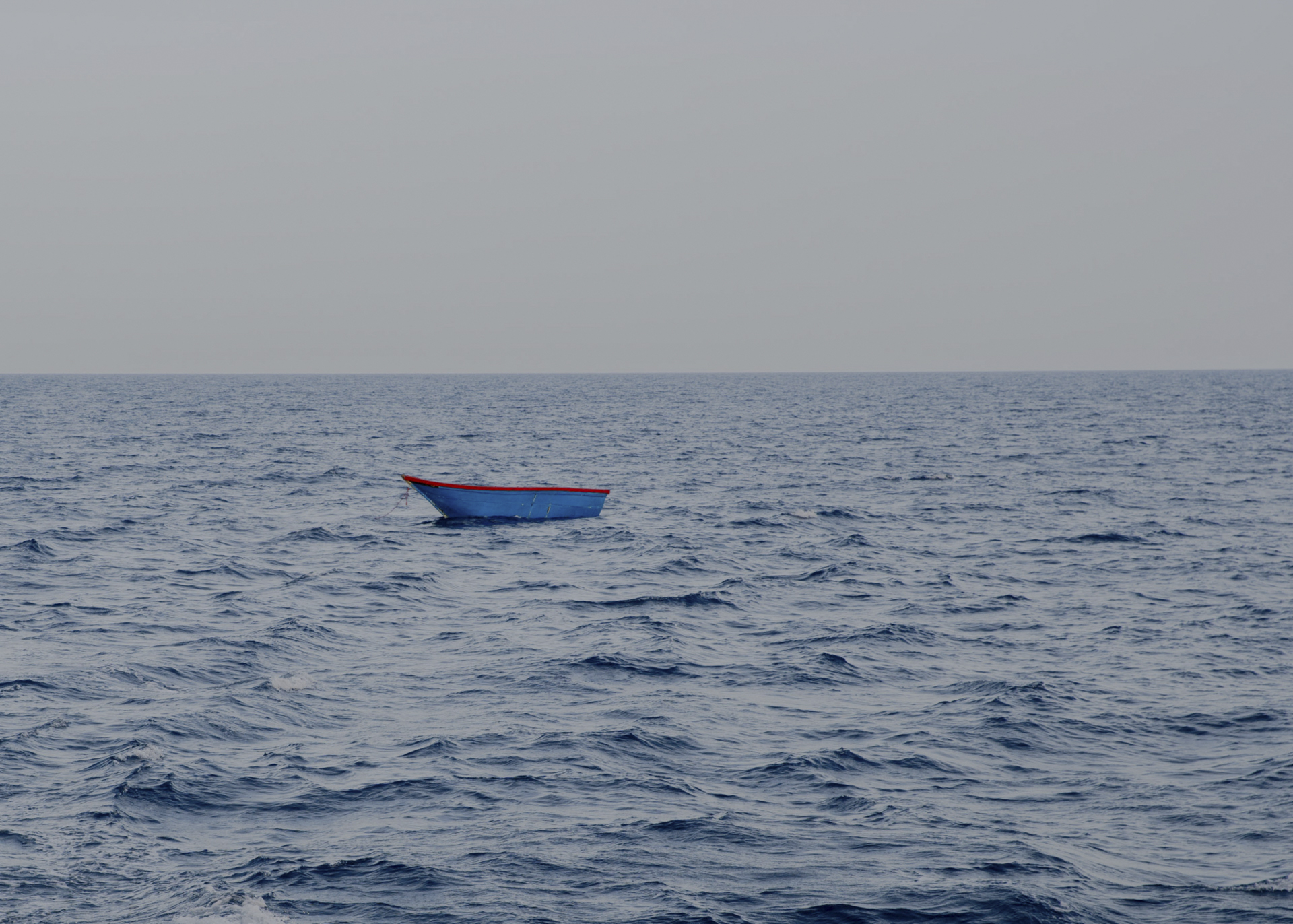 Lockdown in the Mediterranean. Ein leeres Holzboot im Mittelmeer. Weil der Motor nicht mehr zu sehen ist, vermutet die Sea-Watch-Crew, dass die Menschen, die fliehen wollten, von der sogenannten libyschen Küstenwache aufgegriffen und zurück aufs Festland gebracht wurden. 17.06.2020, zentrales Mittelmeer. © Laila Sieber