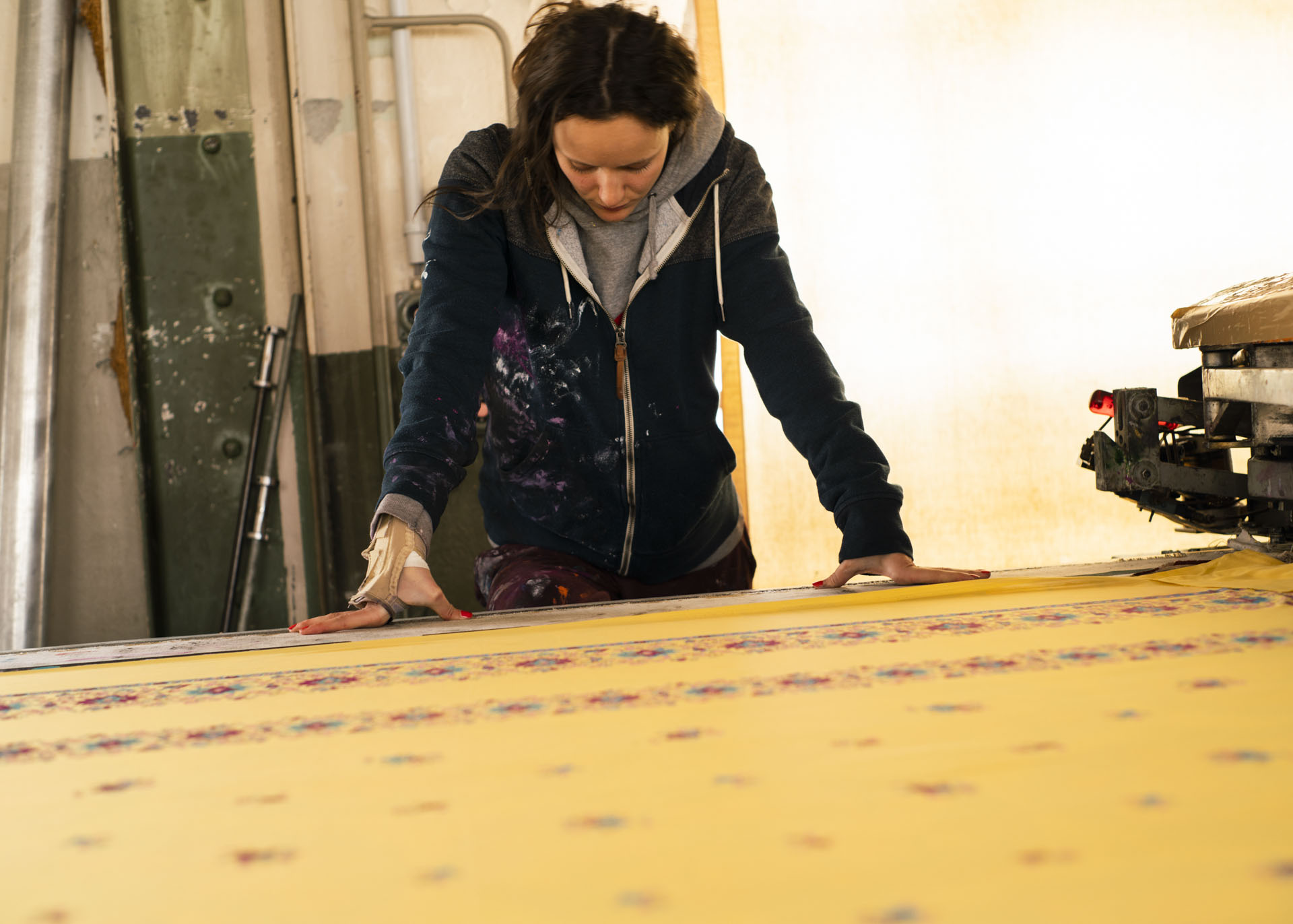 Mitarbeiterin der Textildruckerei TDS beim Überprüfen, ob die Rapporte des Siebdrucks exakt übereinander gedruckt wurden. 19.04.2021, Arbon, Schweiz. © Maidje Meergans
