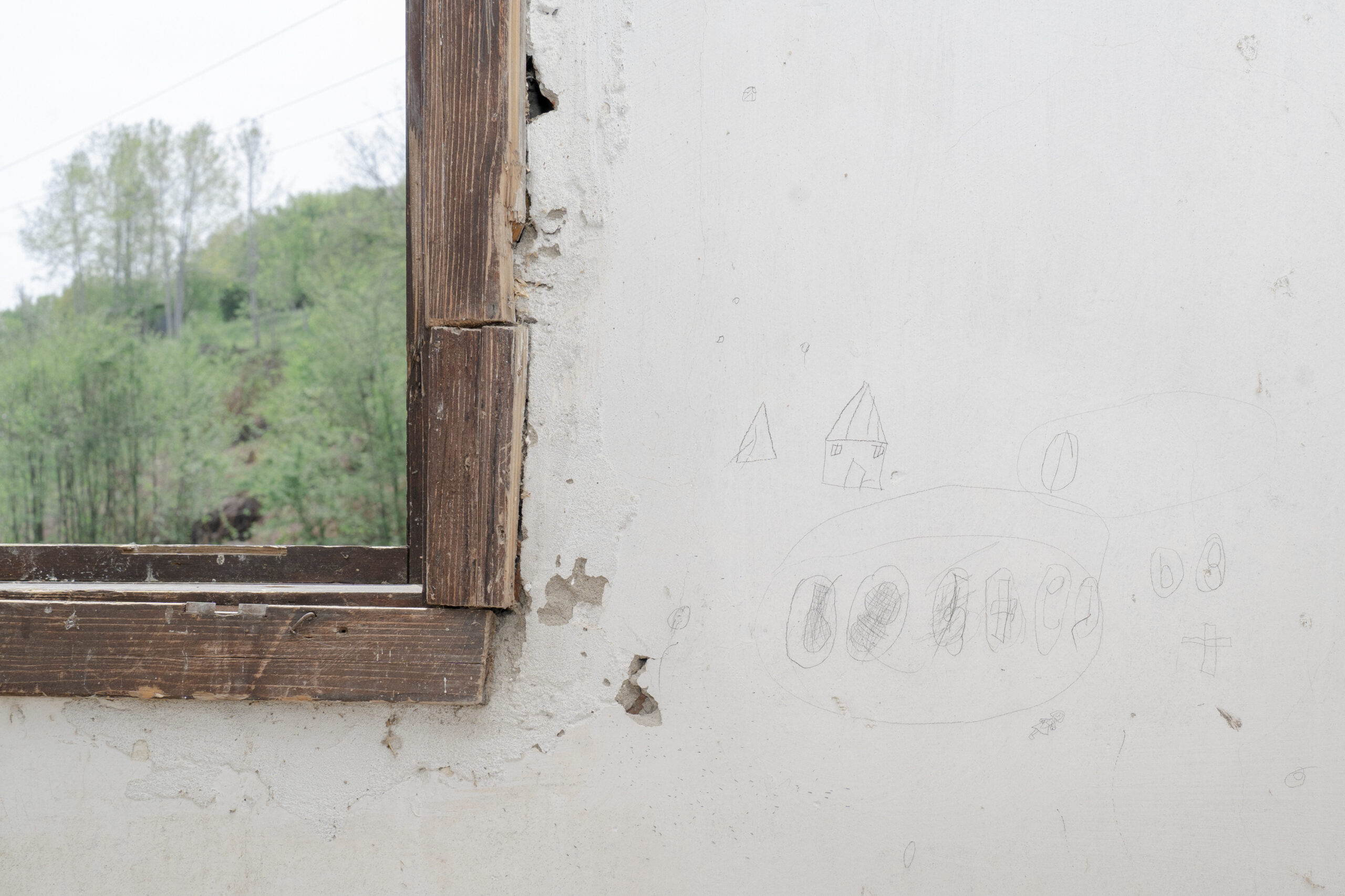 Zeichnungen in einem verlassenen Haus, das auf dem Massengrab «Lazete 1» errichtet wurde. Ein ehemaliges primäres Massengrab in der Nähe von Orahovac, Zvornik, aus dem Massaker von Srebrenica. Bei der Exhumierung durch das ICTY im Jahr 2000 wurde bei der forensischen Analyse festgestellt, dass viele Leichen in sekundäre Gräber verbracht wurden, was auf die Bemühungen hinweist, das Verbrechen zu vertuschen. 11.04.2024, Lazete, Bosnien & Herzegowina, © 2024 Lasse Branding