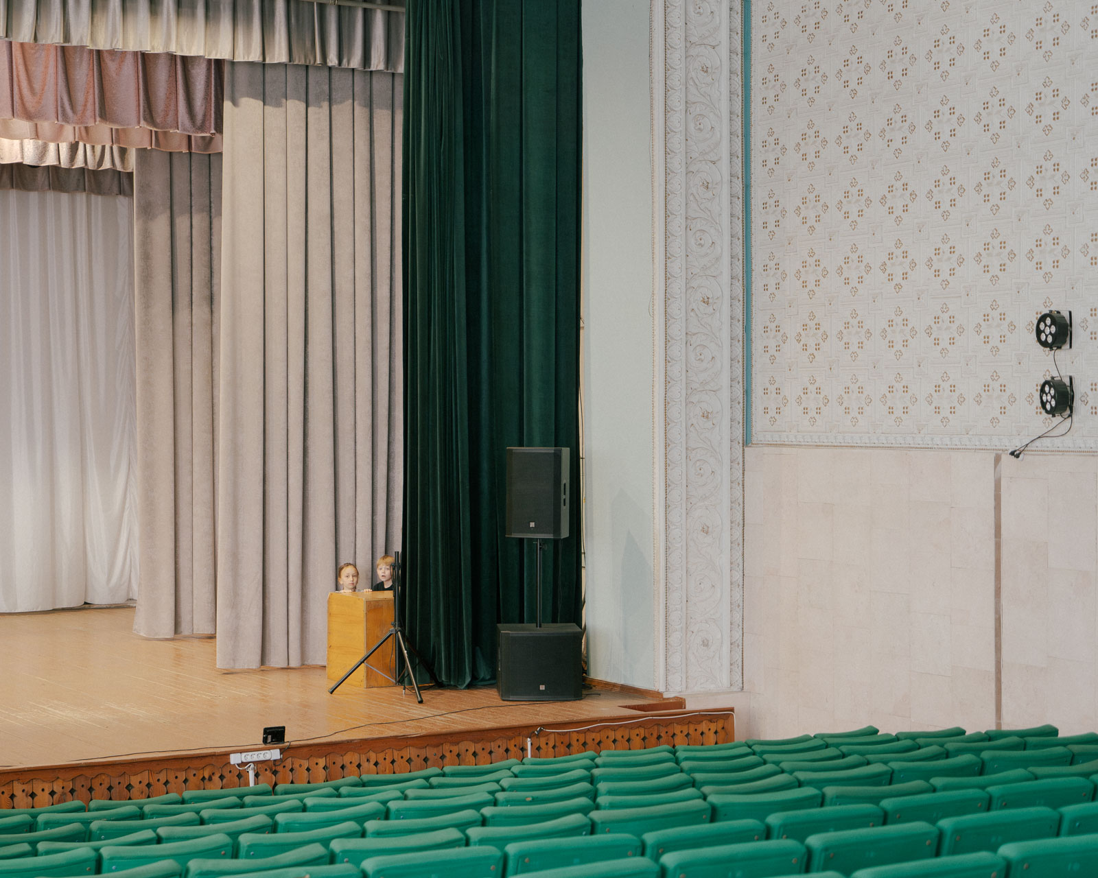 Zwei Kinder verstecken sich auf der Bühne des Kulturhauses von Cocieri. Cocieri liegt am linken Ufer des Dnister. Molovata Nouă und Cocieri sind die einzigen Gemeinden auf der linken Seite des Dnister, die nicht von den transnistrischen Separatisten, sondern von der moldauischen Regierung kontrolliert werden. Vom moldauisch kontrollierten Territorium aus sind die Dörfer nur mit einer Fähre zu erreichen. 18.10.2024, Cocieri, Republik Moldau, © 2024 Julius Nieweler
