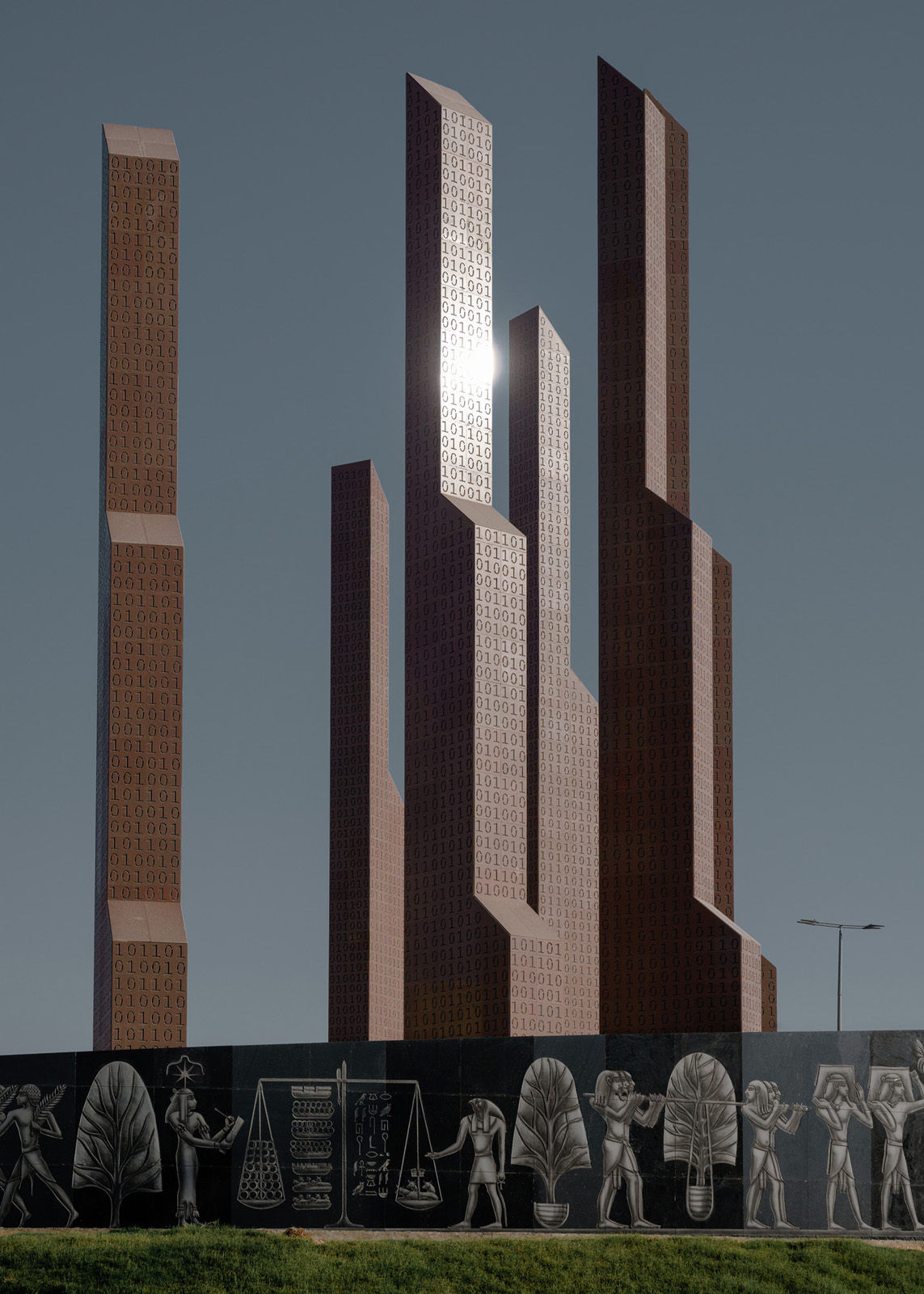 Ein 25 Meter hohes Monument steht auf einer Verkehrsinsel im Zentrum des Finanzbezirks, umgeben von Banken. Im Inneren der Säulen sitzt ein Wachmann und passt auf, dass Niemand den Platz betritt. Außer dem Namen “Marly-Mena Platz” sind vor Ort und im Internet keine Informationen zu seiner Bedeutung verfügbar., 25.06.2023, New Administrative Capital, Ägypten, © 2023 Louis Roth