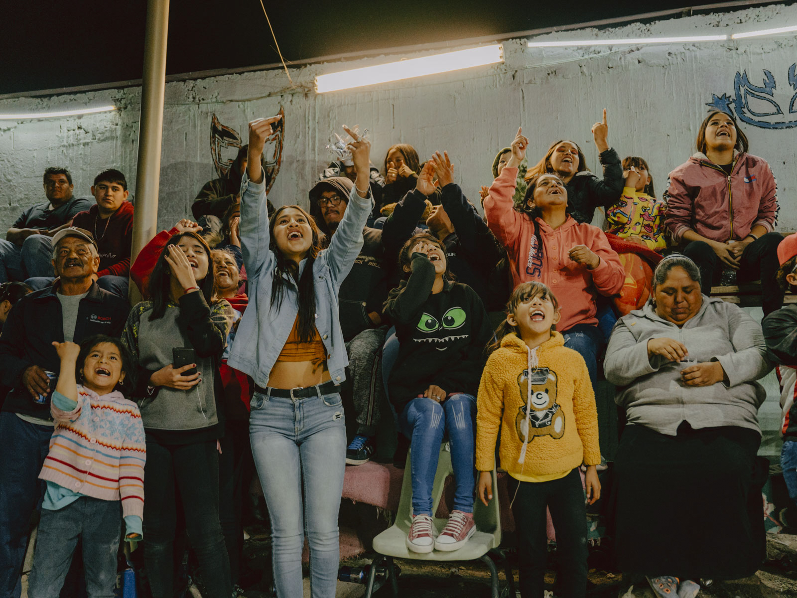 Ein Fan-Block aus Frauen und Mädchen füllt jedes Wochenende die wackeligen Holzbänke der kleinen Arena Morales in Ciudad Juárez und feuert mit voller Hingabe ihre Luchadora-Idole an. Diese Kämpferinnen sind nicht nur Vorbilder, sondern auch Pionierinnen, die mit jedem Kampf gesellschaftliche Normen herausfordern. 12.03.23, Ciudad Juárez, Mexiko, © 2023 Jana Margarete Schuler