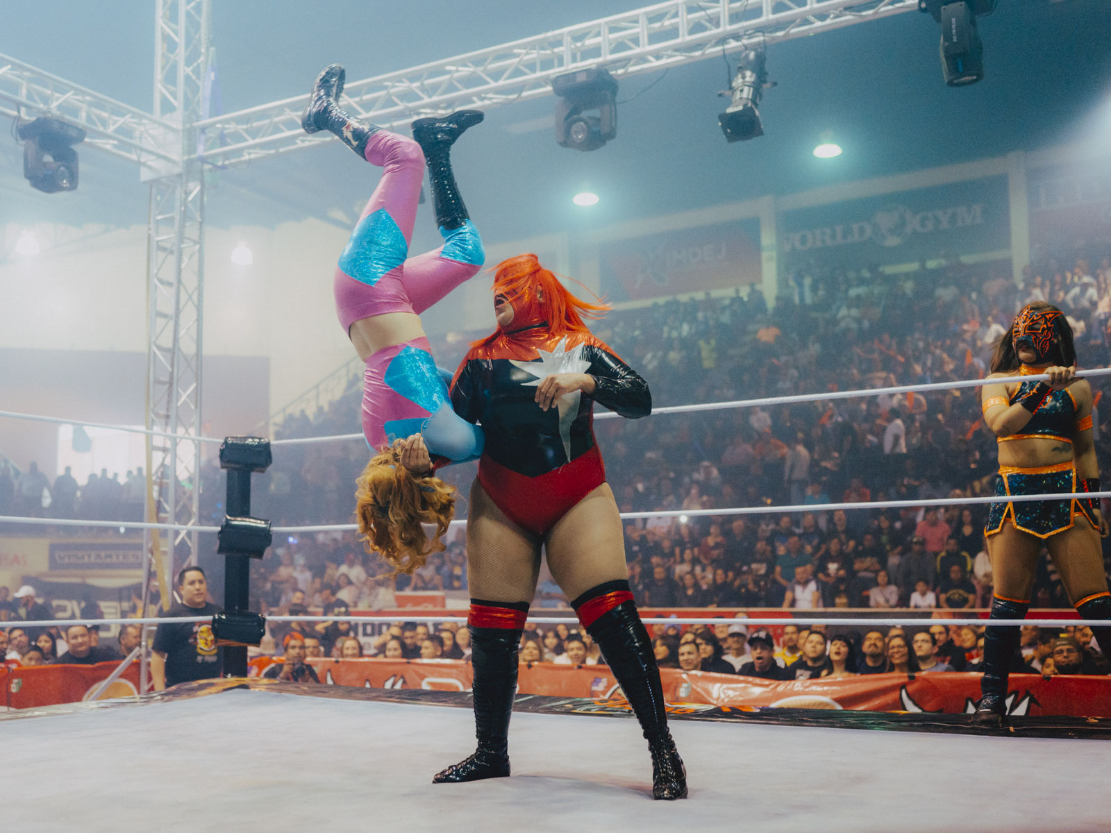 Während eines großen Kampfes in der „Neri Santos“-Arena in Ciudad Juárez schleudert Estrella Diabólica ihre Gegnerin Baby Star durch die Luft. Lucha Libre erfordert extreme körperliche Fitness, wer hier als Luchadora antritt, hat es an die Spitze der Wrestling-Szene geschafft. Die Zuschauer jubeln, während Sayuri am Rand wartet – bereit für ihr Duell. 12.03.2023, Ciudad Juárez, Mexiko, © 2023 Jana Margarete Schuler
