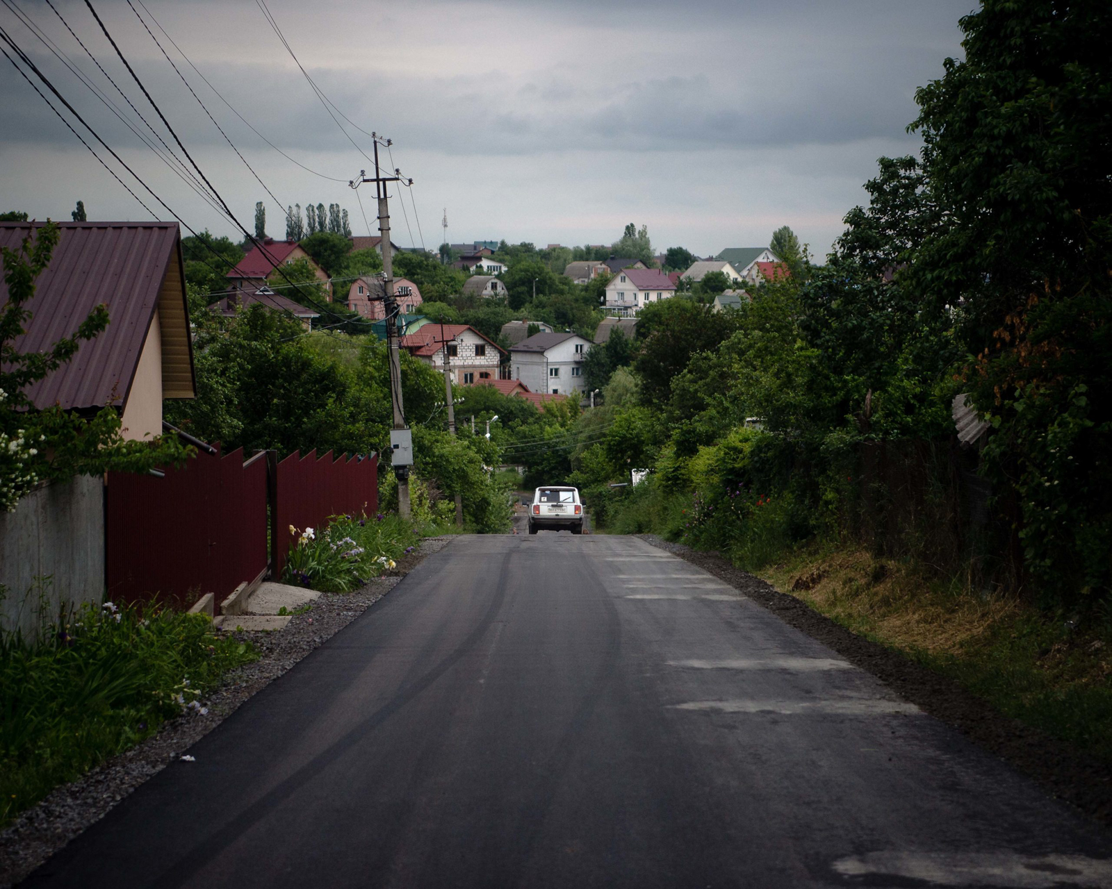 Sasha Glavinsky fährt in einem weißen Lada, seinem Dienstwagen, durch Khmelnytskyi, um einen erkrankten Hundewelpen von der Tierklinik in ein Tierheim zu bringen.   Aufgenommen am 14. Juni 2021 in Khmelnytskyi im Westen der Ukraine, © 2021 Finn Winkler