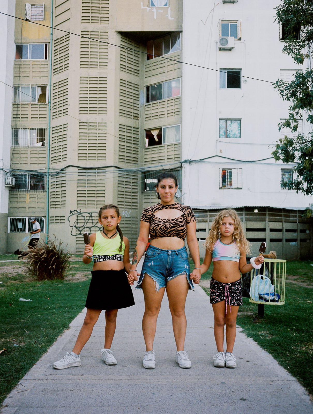 Micaela (26) steht mit ihren beiden Töchtern Mia (11) und Brianna (9) vor ihrem Wohnkomplex in Buenos Aires. «Ich war nie ein Teenager», sagt Micaela. «Ich war gleich eine Mutter.» Mit 15 wurde sie zum ersten Mal schwanger, mit 17 noch einmal. «Die Reaktion meiner Familie war schrecklich. Meine Mutter, mein Vater, meine Onkel und Tanten, alle wollten mich zu einer Abtreibung überreden. Aber ich bin eine sehr entschlossene Frau, man kann mich nicht einfach so umstimmen. Ich habe immer davon geträumt, Mutter zu werden. Und ich habe alle Hürden überwunden, es gegen alle Vorurteile geschafft, meine Töchter Mia und Brianna bei mir zu behalten.» 07.03.2024, Buenos Aires, Argentinien, © 2024 Tiziana Amico