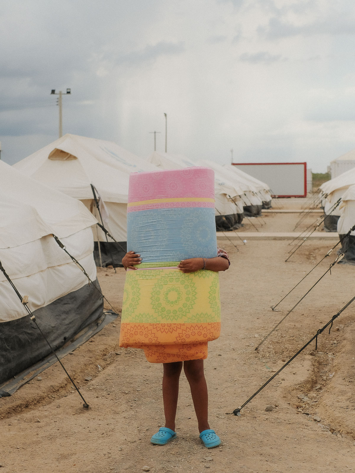Ein Mädchen transportiert ihre Decke im UNHCR-Flüchtlingslager in Maicao. Das Lager bietet Unterkunft für Tausende, die vor der Krise in Venezuela geflüchtet sind. 19.09.2019, Maicao, Kolumbien, © 2019 Tiziana Amico
