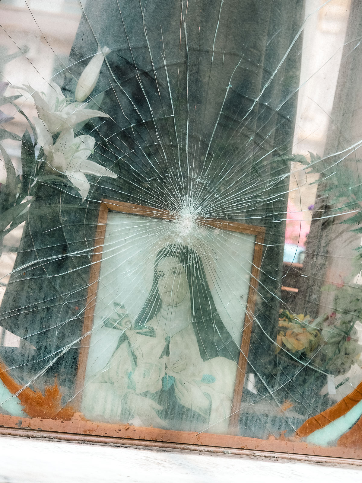 Zerbrochenes Glas eines Marienaltars. Die Jungfrau Maria, das Ideal der reinen, opferbereiten Frau, steht seit Jahrhunderten als zentrales religiöses Vorbild in der italienischen Gesellschaft. Viele Frauen wachsen in einer Welt auf, in der Weiblichkeit nur in starren Kategorien existiert: rein wie Maria oder «gefallen» wie Maria Magdalena. 20.06.2025, Palermo, Italien, © 2025 Tiziana Amico