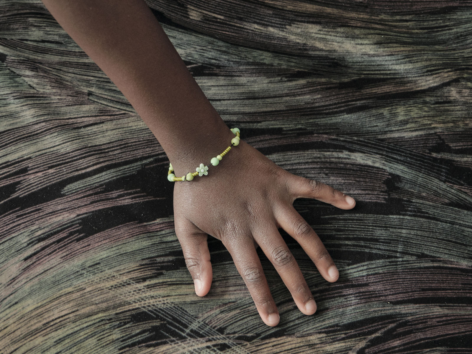 Die Hand von Alicia, mit dem Armband das sie selbst gebastelt hat. Sie ist 8 Jahre alt und lebt mit ihrer Mutter in der Unterkunft in Vilnius., 23.08.2023, Vilnius, Litauen, ©2023 Carlotta Steinkamp