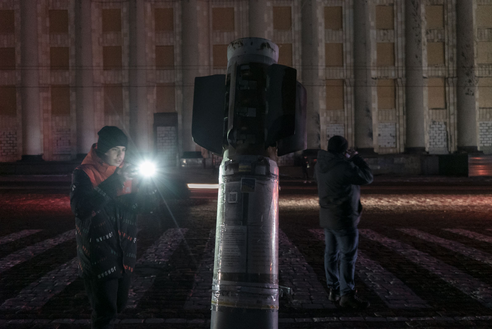 Ein Jugendlicher fotografiert eine Blindgänger-Rakete, die auf dem Majdan Swobody in Charkiw vor einem regionalen Verwaltungsgebäude in den Asphalt eingelassen worden ist. Sie soll an die russische Bombardierung der Stadt erinnern. Zu Beginn der russischen Invasion auf die Ukraine wurde dieser Platz und das Gebäude von 