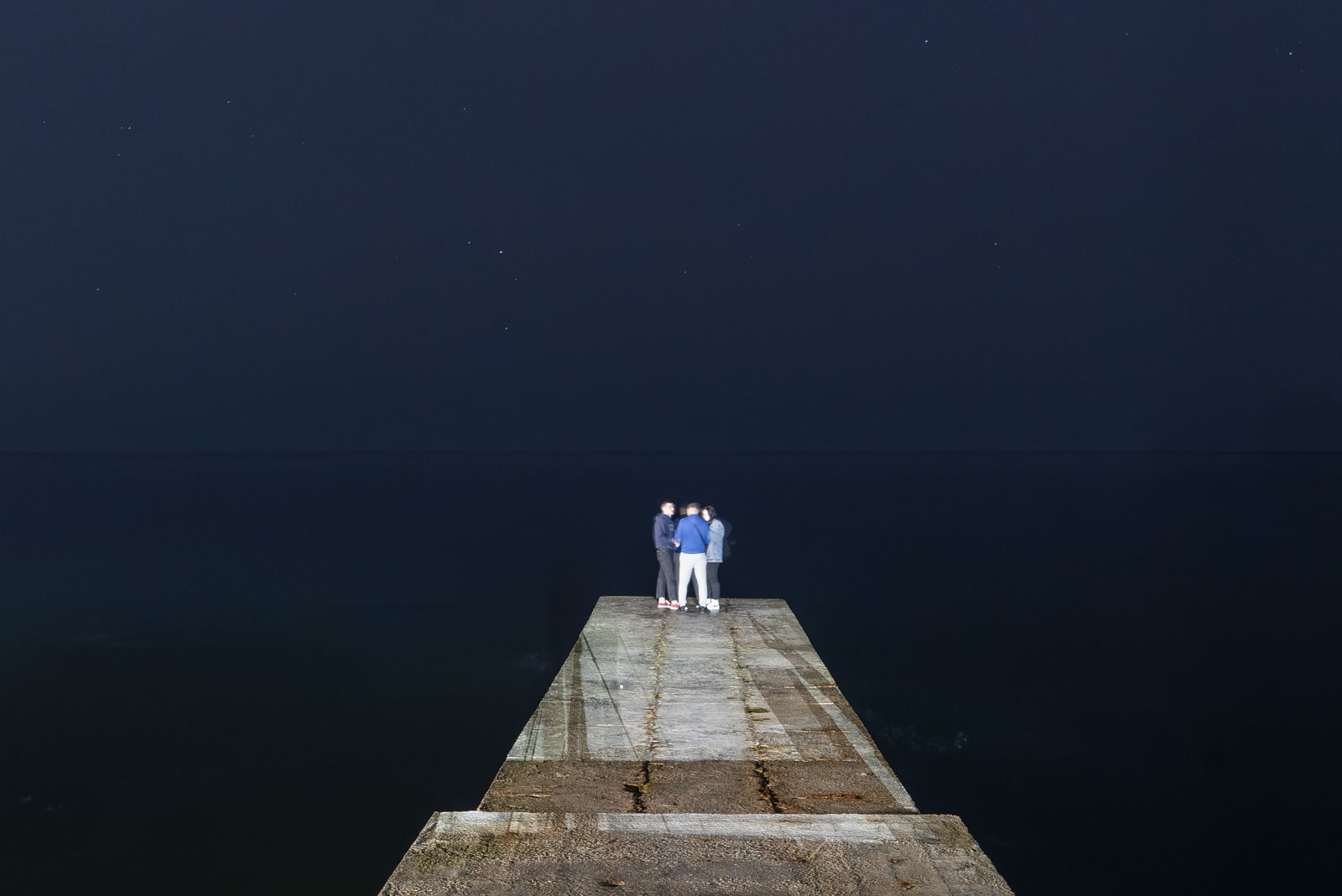 Die Strände und Piers am Schwarzen Meer sind bei jungen Leuten in Odesa sehr beliebt – selbst an kühlen, dunklen Frühlingsnächten. Am Horizont liegen russische Kriegsschiffe, die die Stadt und die gesamte Ukraine regelmäßig mit Lenkraketen beschießen. 14.04.2023, Odesa, Ukraine. © 2023 Gerd Waliszewski