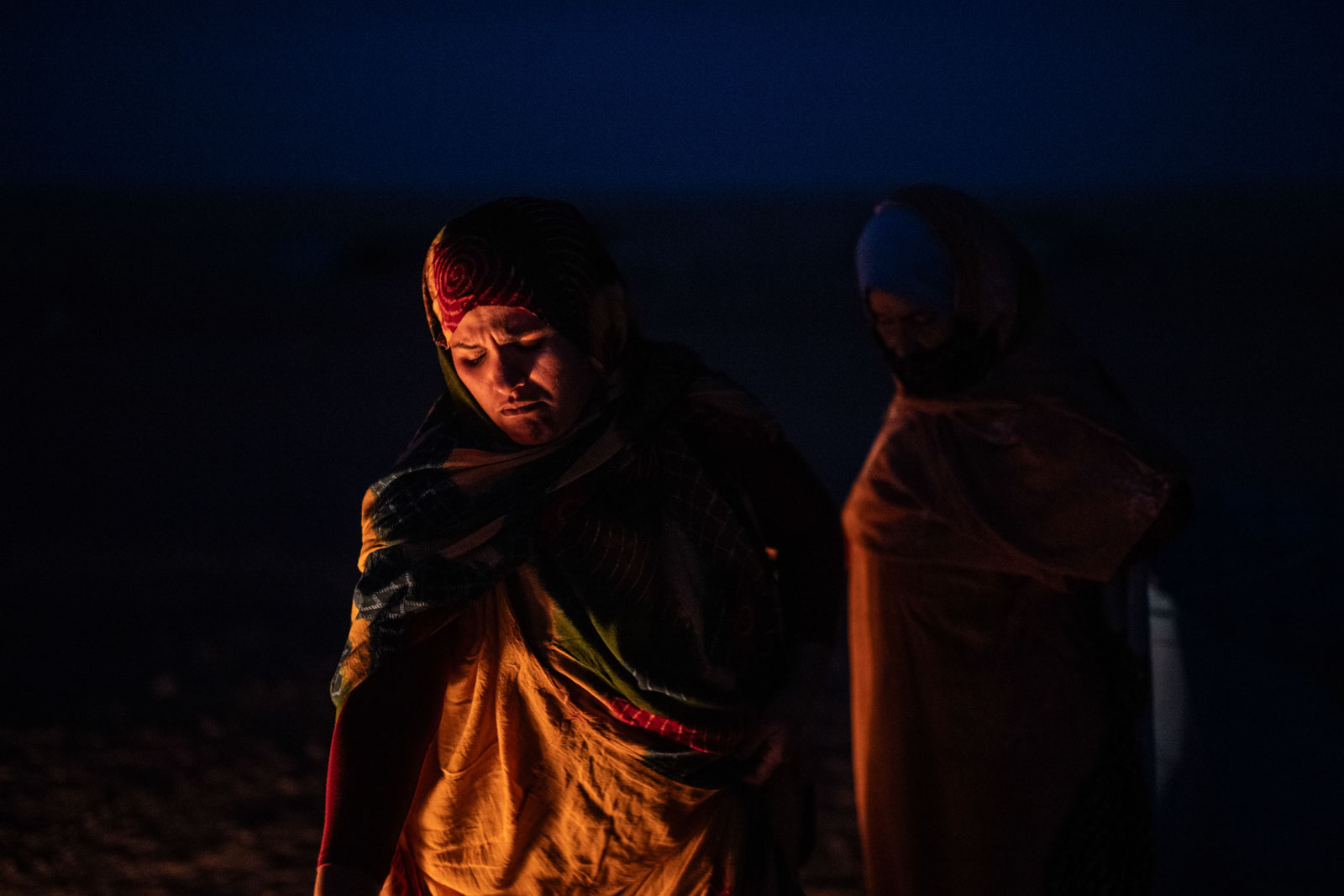 Vor 50 Jahren drang die Kolonialmacht Marokko in die Westsahara ein. Tausende Sahrauis flohen in die lebensfeindliche Hamada-Wüste, wo sie seitdem in Flüchtlingslagern ausharren, Najla Mohammad Lamin im Feuerlicht in der Hamada Wüste, 06.12.2025, Hamada Wüste nähe Tindouf, Algerien, © 2025 Niklas Thalmann